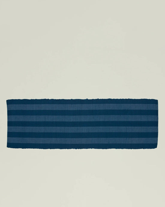The Essential Floor Runner in Navy by Hawkins New York features dark blue stripes and is crafted from recycled fibers, shown laid flat on a plain, light-colored background.