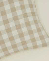 Close-up of the Hawkins New York Essential Gingham Pillow in Ivory/Flax, 18x18 inches, made from European linen with a down insert, resting on a light-colored surface.