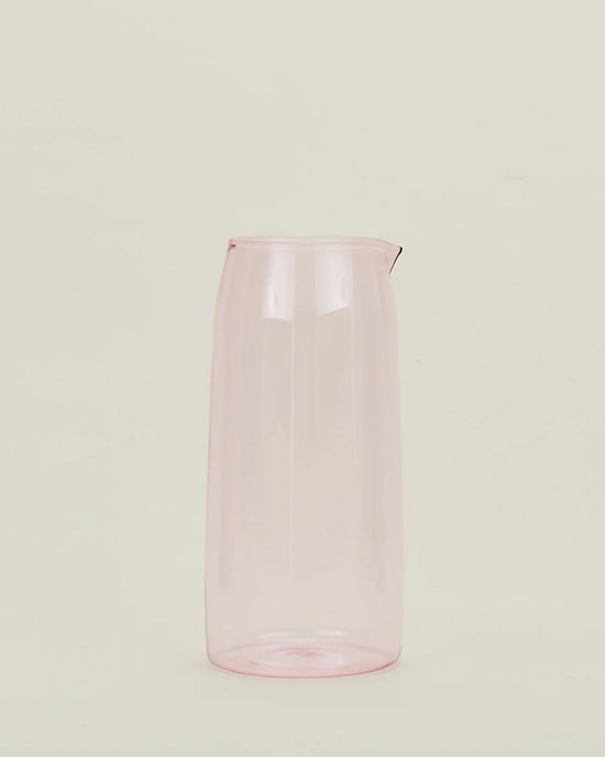 The Hawkins New York Essential Glassware - Pitcher in Blush, a translucent pink pitcher with a spout, stands upright against a plain off-white background.