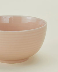 A close-up of a blush Essential Large Bowl from Hawkins New York, featuring a ribbed texture against a plain background. This elegant stoneware bowl comes in a set of 4 and is dishwasher safe.