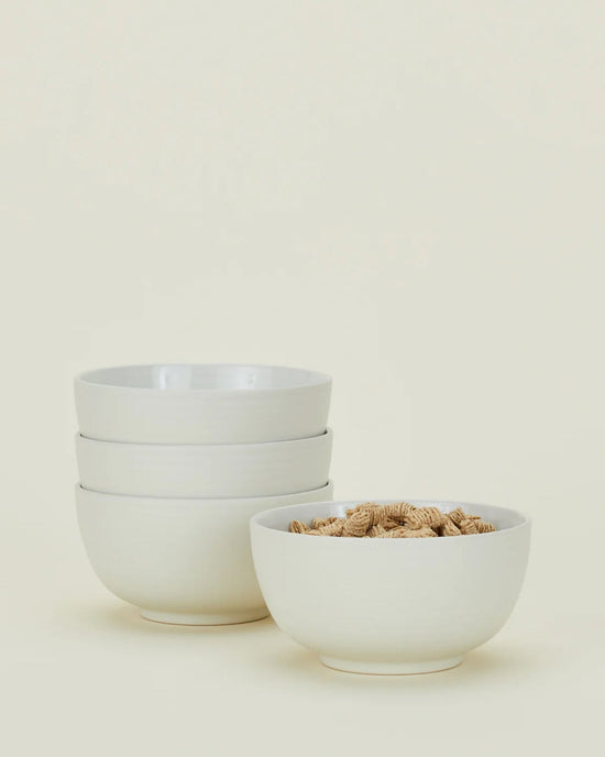 Four Hawkins New York Essential Large Bowls in Bone are shown—three stacked and one with cereal—against a plain light background.