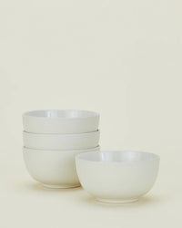 Four Essential Large Bowls in Bone by Hawkins New York are displayed against a light background, with three stacked together and one placed separately in front.