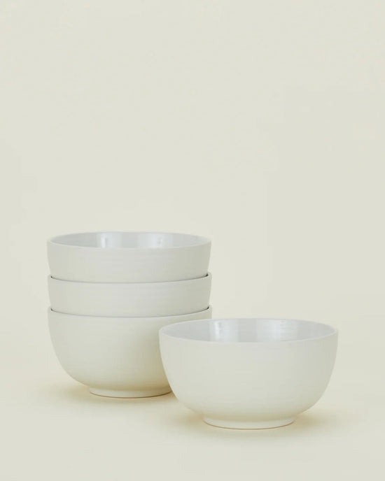 Four Essential Large Bowls in Bone by Hawkins New York are displayed against a light background, with three stacked together and one placed separately in front.
