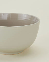 A close-up of Hawkins New York Essential Large Bowls in Light Grey—set of 4—with a light grey exterior and glossy, darker interior, ideal for those seeking large stoneware bowls or dishwasher safe dinnerware.