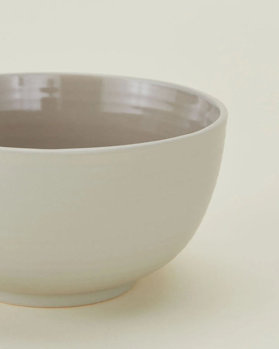 A close-up of Hawkins New York Essential Large Bowls in Light Grey—set of 4—with a light grey exterior and glossy, darker interior, ideal for those seeking large stoneware bowls or dishwasher safe dinnerware.