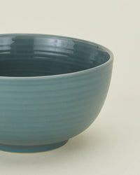 A close-up of Hawkins New York’s Essential Large Bowls in Peacock (set of 4), featuring blue ribbed ceramic stoneware, shown against a plain light background.