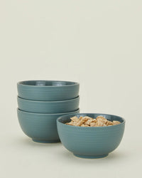 A set of four Essential Large Bowls in Peacock by Hawkins New York are stacked, with the front bowl filled with shredded wheat cereal.