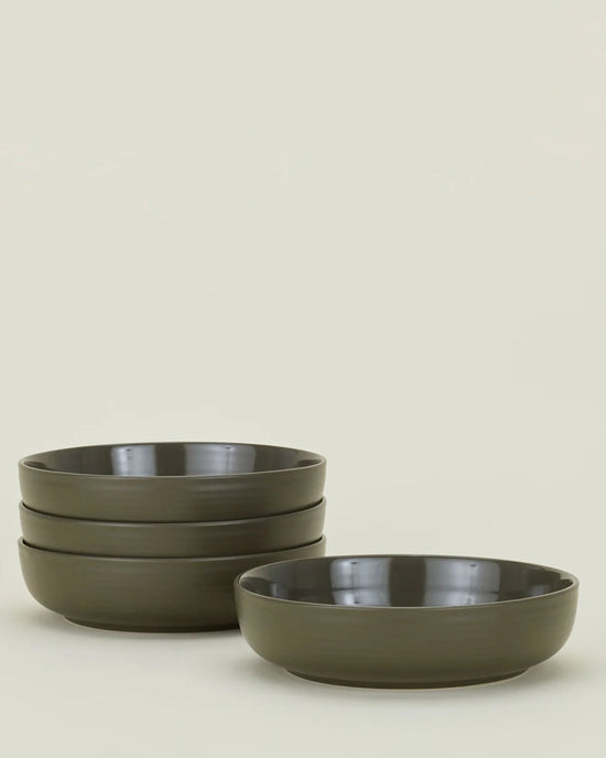 A set of four matte olive Essential Low Bowls from Hawkins New York are stacked on the left, with a fifth bowl placed separately on the right, all against a plain light background.