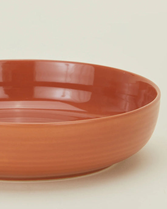 A close-up of the Hawkins New York Essential Low Bowls in Terracotta, a set of 4, showcases their round, shallow stoneware design against a plain light background.