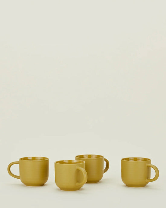 Four mustard Essential Mugs by Hawkins New York are arranged in a row on a plain light background, highlighting this vibrant set of 4.