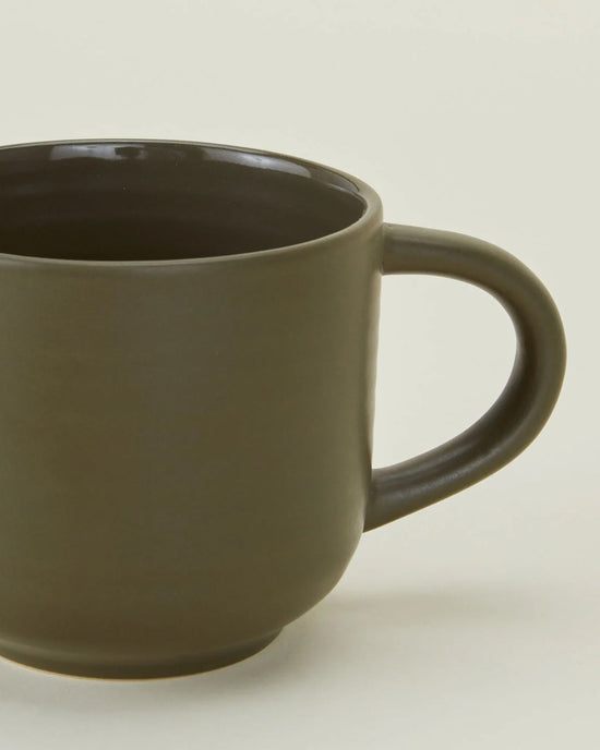 A close-up of Hawkins New Yorks Essential Mugs in Olive—set of 4—plain stoneware mugs with handles, set against a light background, offering an elegant option for quality drinkware.