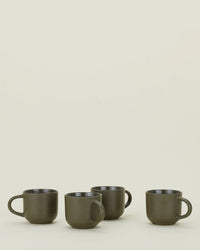 A set of four Hawkins New York Essential Mugs in Olive is lined up on a light surface with a plain off-white background.