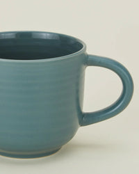 A close-up of a Hawkins New York Essential Mug in Peacock, featuring a large handle from a stylish set of 4 stoneware mugs, shown against a plain light background.