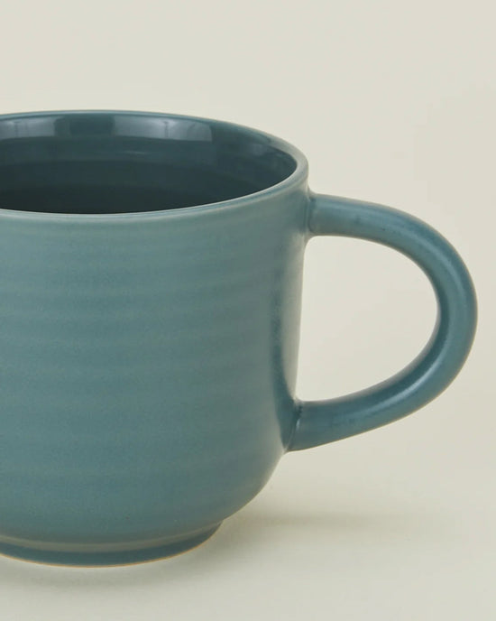 A close-up of a Hawkins New York Essential Mug in Peacock, featuring a large handle from a stylish set of 4 stoneware mugs, shown against a plain light background.