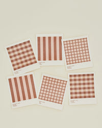 A set of 6 Essential Swedish Dishcloths in Blush/Terracotta by Hawkins New York is arranged on a light surface, featuring red and white checkered or striped patterns inspired by classic Swedish design.