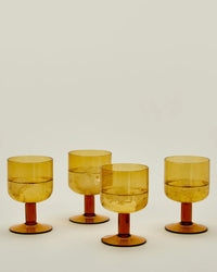 A Set of 4 Stemmed Simple Seeded Glassware in Amber from Hawkins New York, featuring wide bowls and short stems, is displayed on a neutral background to highlight their elegant design.