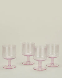 Four blush Stemmed Simple Seeded Glassware goblets by Hawkins New York are arranged on a neutral background, highlighting the elegant design of this set of four.