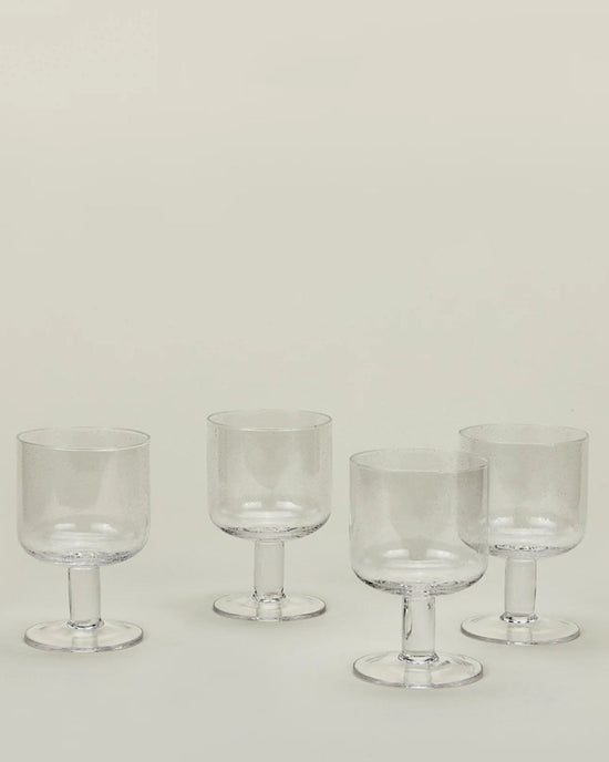 A set of 4 Hawkins New York Stemmed Simple Seeded Glassware in Clear is arranged on a light surface with a neutral background.