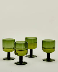 A set of four olive stemmed Simple Seeded Glassware by Hawkins New York is displayed on a plain, light background. Subtle bubbles in the glass evoke classic charm and timeless style.