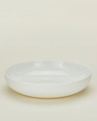 A set of 4 Simple Porcelain Low Bowls by Hawkins New York, featuring a plain, round white design with a subtly raised edge, displayed on a light cream background.