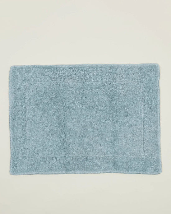 The Hawkins New York Simple Terry Bath Mat in Sky, featuring a soft, plush texture and rectangular shape, is displayed against a plain off-white background.