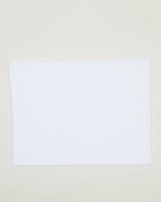 The Hawkins New York Simple Terry Bath Mat in White, crafted from cotton, is laid flat on a light-colored surface.