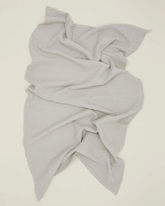 The Hawkins New York Simple Waffle Bath Sheet in Light Grey, made from stonewashed cotton with a textured waffle weave, is shown laid out and softly crumpled on a light surface.
