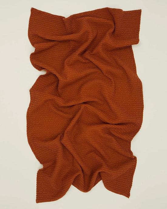 The Hawkins New York Simple Waffle Bath Sheet in Terracotta is displayed on a light background, its soft folds and texture giving it a casual, relaxed look.