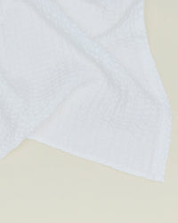 The Simple Waffle Bath Towel in White by Hawkins New York, made in Portugal, features a subtle grid texture and is shown draped against a light, neutral background.