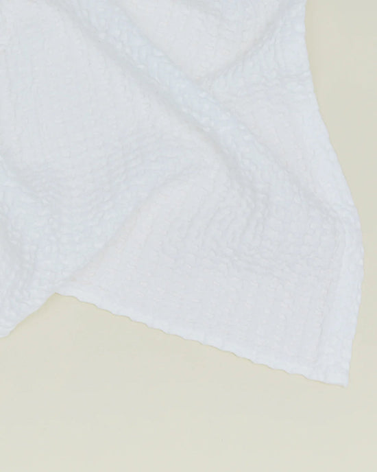 The Simple Waffle Bath Towel in White by Hawkins New York, made in Portugal, features a subtle grid texture and is shown draped against a light, neutral background.