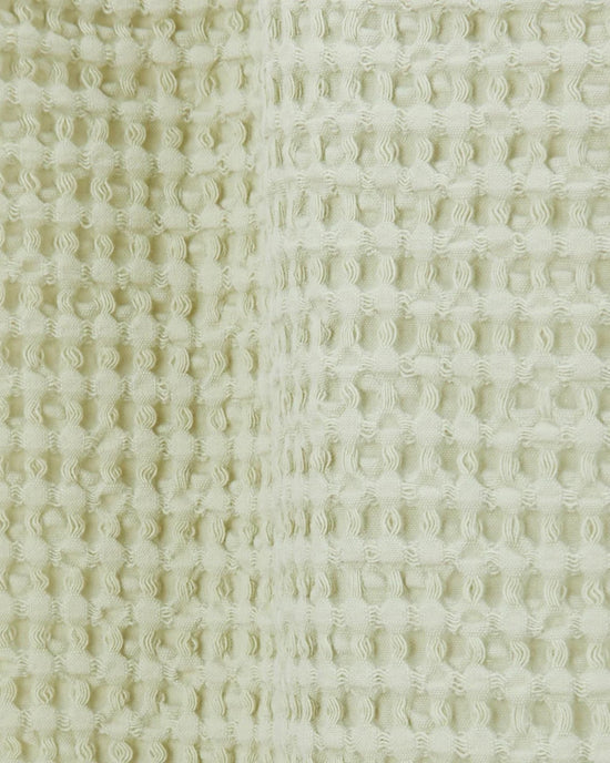 Close-up of the Simple Waffle Shower Curtain in Sage by Hawkins New York, featuring a textured cotton fabric with a distinctive waffle pattern.