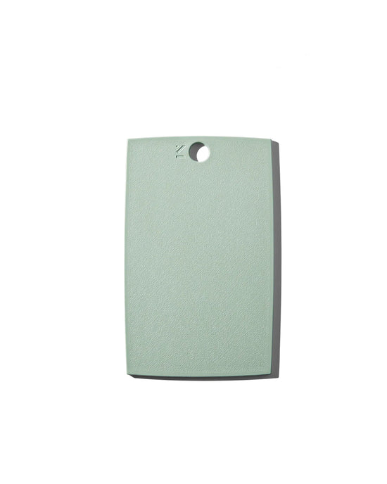 The (mini) reBoard® | Moss by Material is a rectangular, light green cutting board made from sustainable materials with a hole near the top center, shown on a white background.