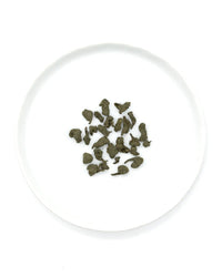 A white plate holds loose, dried Ginseng Oolong Tea leaves from Onyx Coffee Lab, echoing the premium quality of their 12 sachet offering.