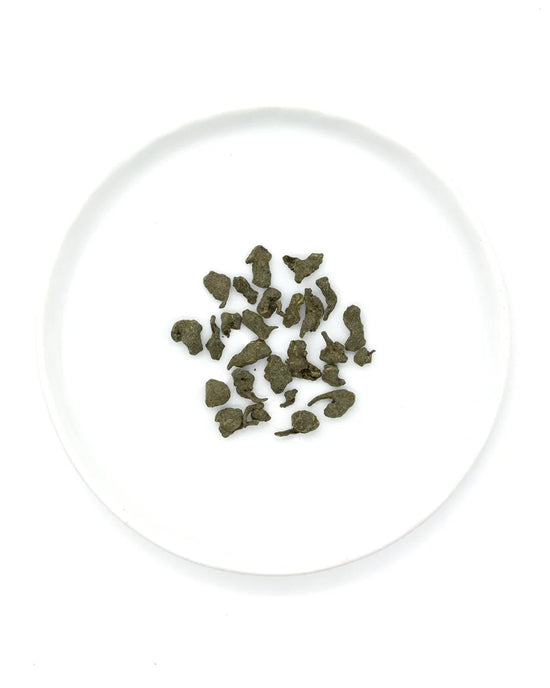 A white plate holds loose, dried Ginseng Oolong Tea leaves from Onyx Coffee Lab, echoing the premium quality of their 12 sachet offering.