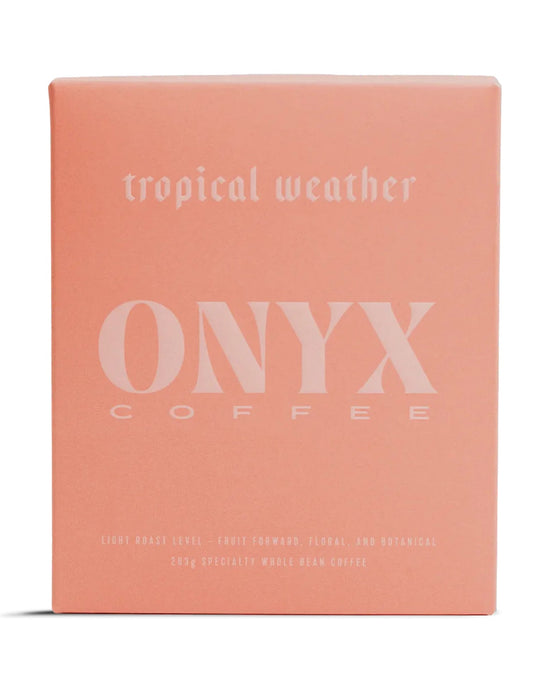 A pink box labeled Tropical Weather Coffee | 10oz by Onyx Coffee Lab features a light roast, fruit-forward, floral, and botanical whole bean Ethiopian coffee.