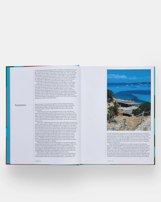 An open copy of The Spanish Mediterranean Islands Cookbook by Phaidon Press displays text about Formentera alongside a vibrant photo of its rocky coastline and blue sea, with additional details below on Balearic Islands cuisine.