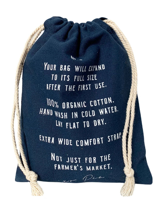 The French Market Bag No.2 in Navy by PILLOWPIA is made from 100% organic cotton with white text detailing care instructions and wide comfort straps—ideal for a chic, eco-friendly carryall.
