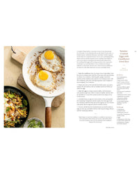 Fried eggs in a pan with a side of salad on a white background
