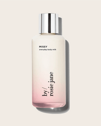 Rosie Jane Missy Everyday Body Milk features a hydrating formula, silver cap, white-to-pink gradient glass bottle, and minimalist black text on a beige background.