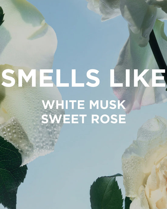 Close-up of dewy white roses on a light blue background with bold white text: Smells like Rosie Everyday Body Wash by Rosie Jane—white musk and sweet rose.