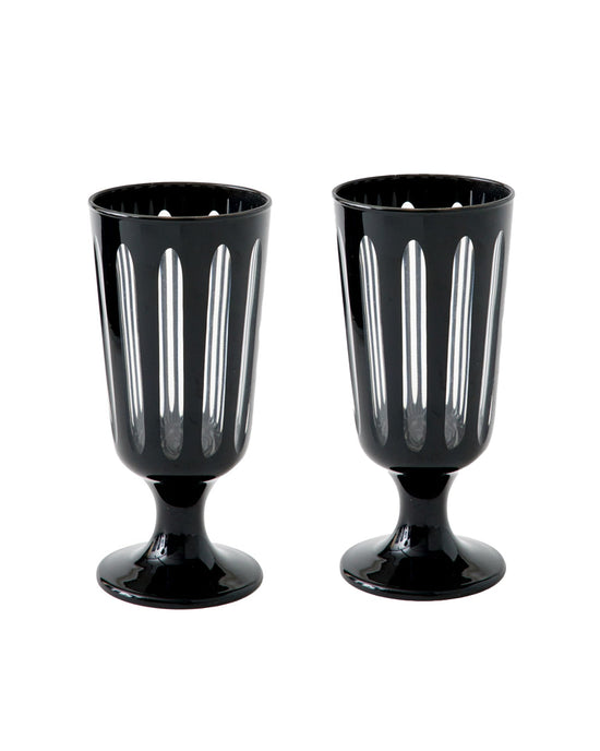 The Empire Footed Ale Tuxedo Set/2 by SIR / MADAM features two black glass goblets with vertical cutout patterns and a short pedestal base, reminiscent of classic Empire designs, shown side by side on a white background.