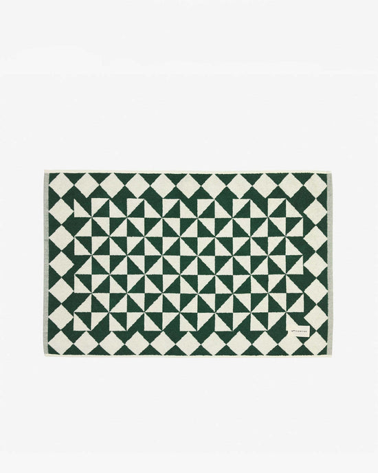 The Slowtide Gatsby Bath Mat in Sequoia is a rectangular, ultra-soft bath mat featuring a green and white geometric pattern, crafted from sustainably sourced cotton and shown on a plain white background.