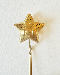 The Quiet Botanist’s Tea Steeper - Star features a gold, star-shaped design with a smiling face, perfect for tea lovers and shown on a plain white background.