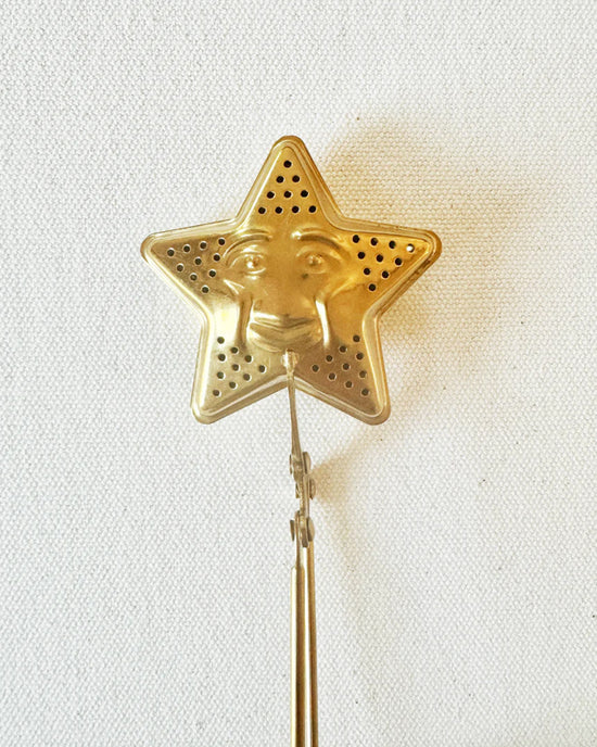 The Quiet Botanist’s Tea Steeper - Star features a gold, star-shaped design with a smiling face, perfect for tea lovers and shown on a plain white background.