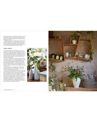 A magazine spread from "The Artistry of Flowers" by Random House displays text with floral arrangements and, opposite, shelves with mugs, teapots, and plants over a table set with plates and a white pitcher—perfect home decor inspiration.