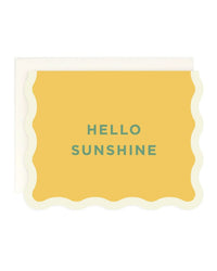 The Hello Sunshine | Single Card by Amy Heitman is a blank greeting card with a scalloped white border, yellow center, and "HELLO SUNSHINE" in green capitals. An envelope is partially visible behind the card.