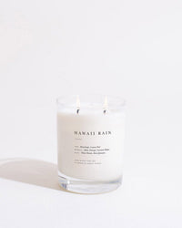 The Brooklyn Candle Studio Hawaii Rain Classic 2-Wick Candle, made of white soy wax in a clear glass jar, features notes of dewdrop, lemon peel, white woods, and jasmine.