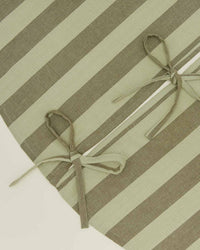 Close-up of the Hawkins New York Essential Striped Tree Skirt in Olive/Sage, featuring wide olive and sage stripes, two fabric bows, and a buttonhole-style slit.
