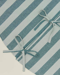 Close-up of blue and white striped fabric with two tied bows and a visible seam, similar to the Essential Striped Tree Skirt in Sky/Peacock by Hawkins New York.