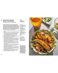 A plate of roasted salmon on bean sprouts, cabbage, and greens with orange dressing sits beside water and a jar of dressing—the perfect inspiration for your next cookbook, The Salad Project by Random House.